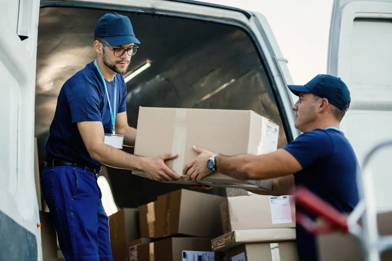 Delivery men loading carboard boxes in a van while getting ready